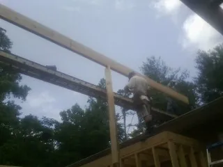 Carpenter setting a ridge beam over a new addition frame — Ice Dam Removal by Roofing Brothers in Deltaville