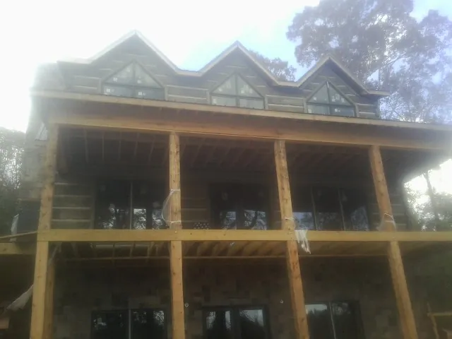 Dormers and porch framing on a large log home under construction — Roof Coating work by our crew in Deltaville