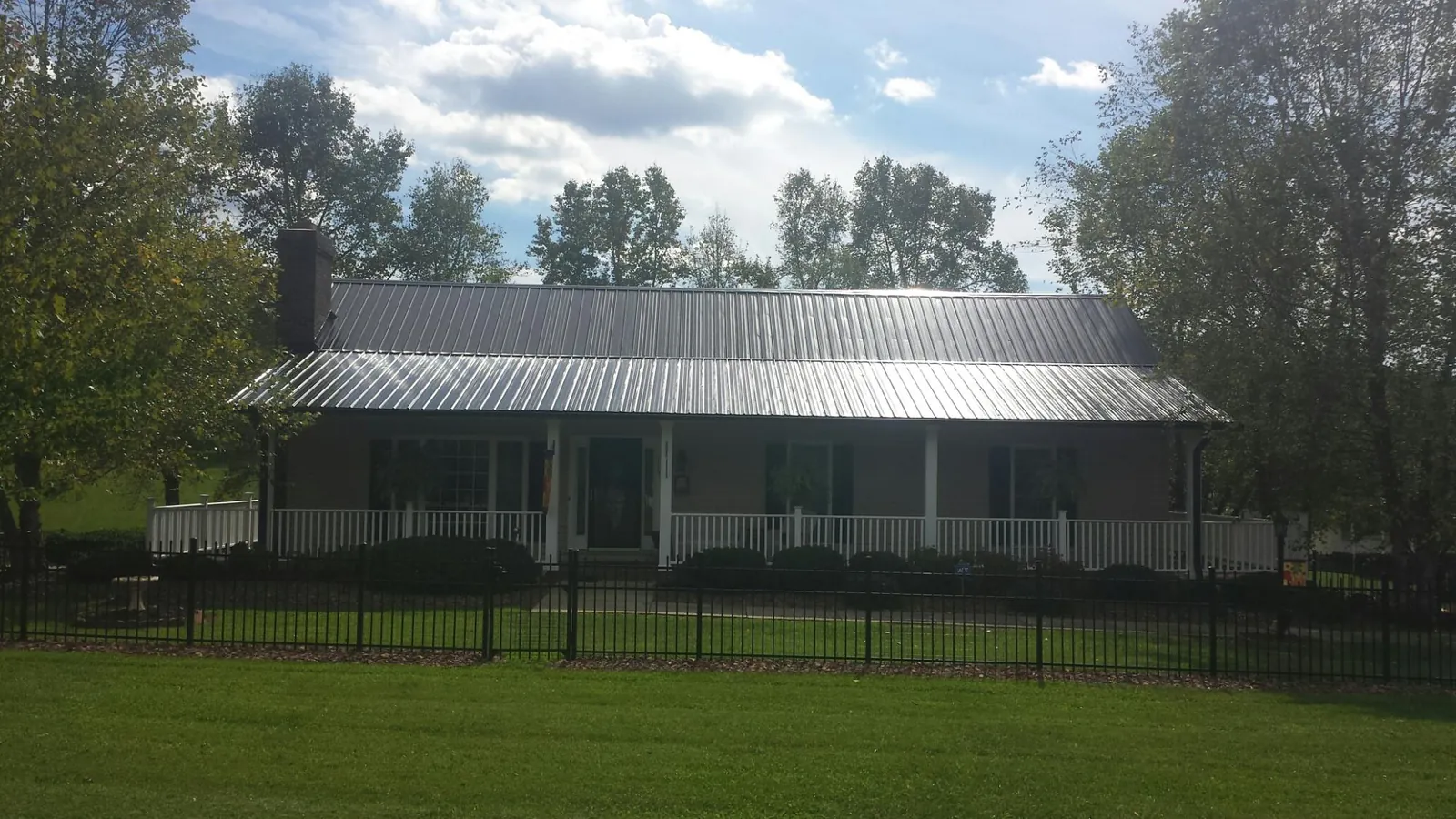 Gray metal roof on a brick ranch with a full width front porch — Gutter Guard Installation work by our crew in Deltaville