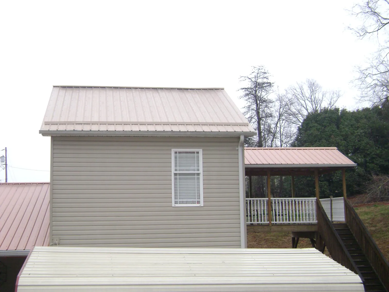 Tan metal roofs on a two story addition and attached porch, from a Roof Replacement job in Deltaville
