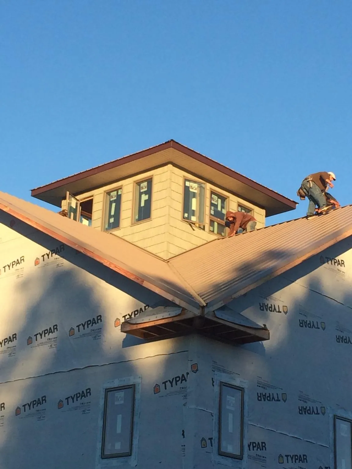 Roofers working around a rooftop cupola on a new metal roof at sunset — Roof Waterproofing in Deltaville by Roofing Brothers